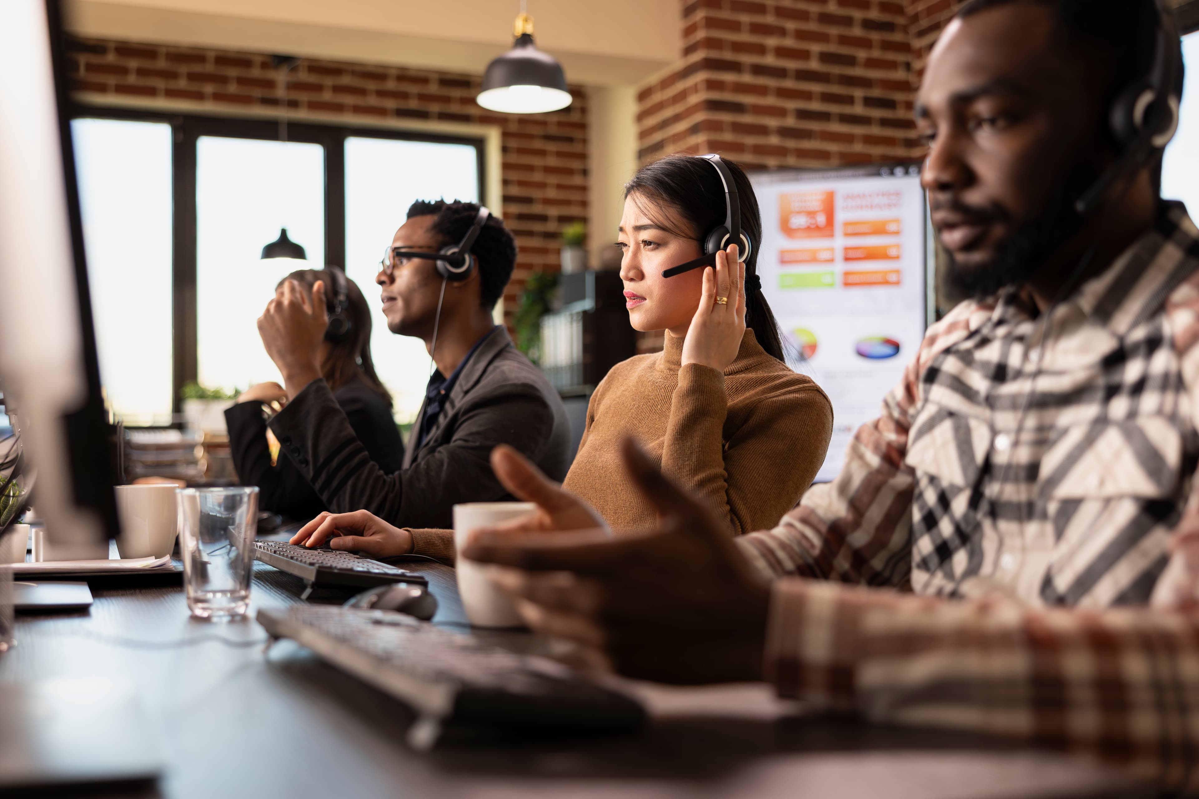 Kundeserviceteam i arbeid med hodetelefoner og bærbar PC