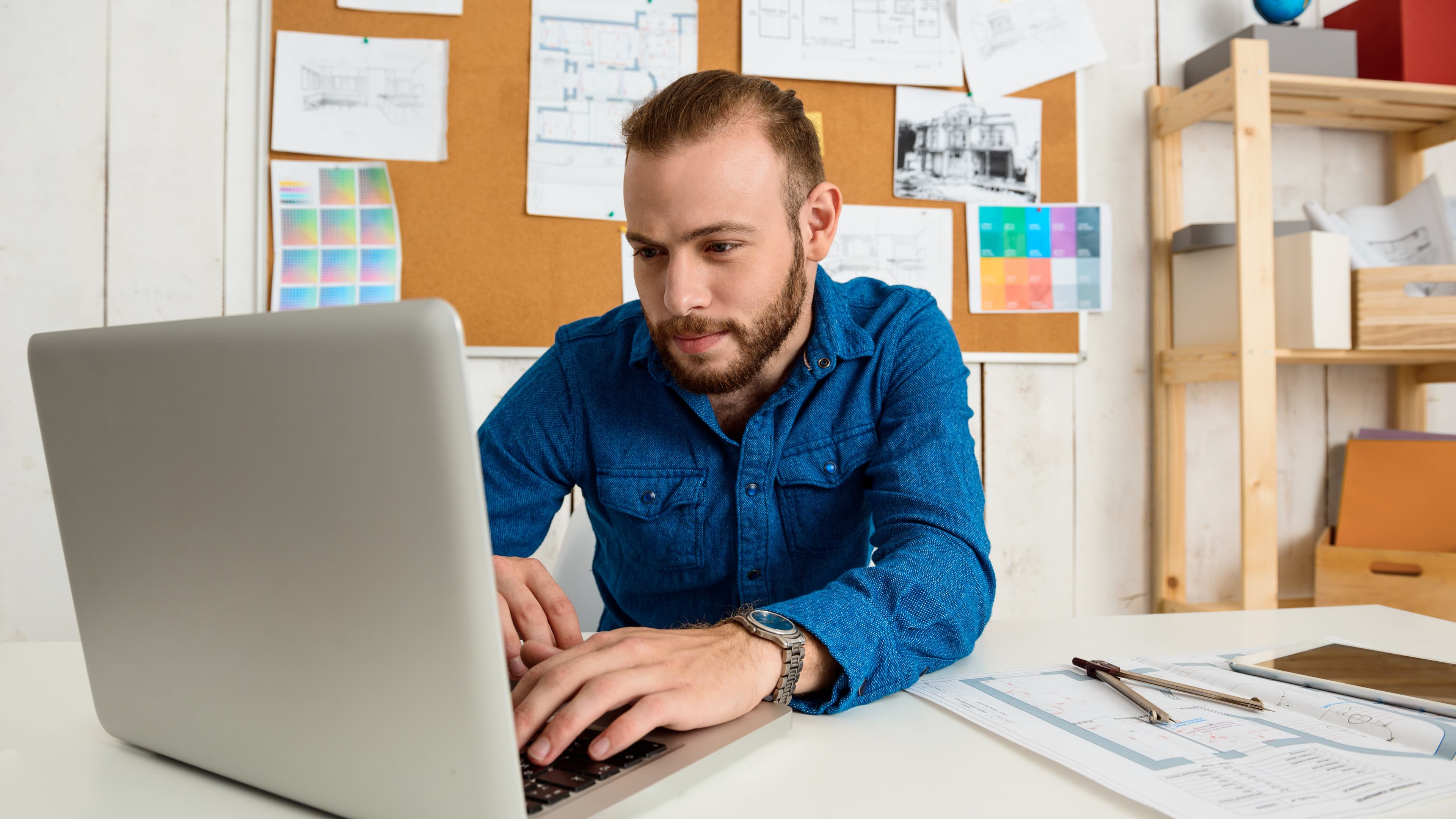 Ansatte samarbeider om dokumenter på bærbare datamaskiner i et moderne kontorlandskap