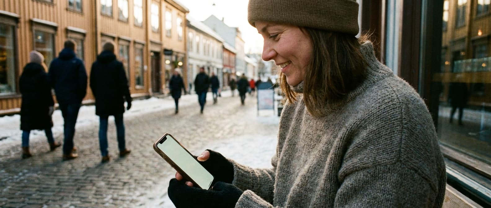 Norsk småbedriftseier ser på mobilskjerm med SMS-varsel fra kunde